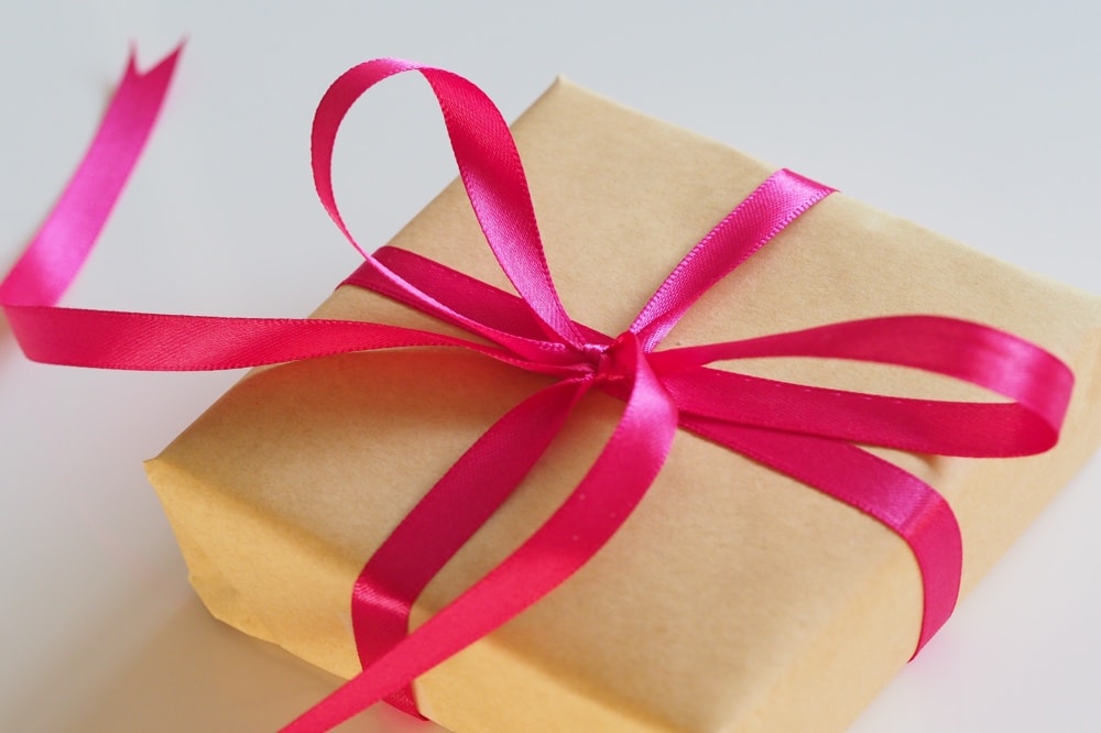 present gift wrapped in brown paper with a pink ribbon
